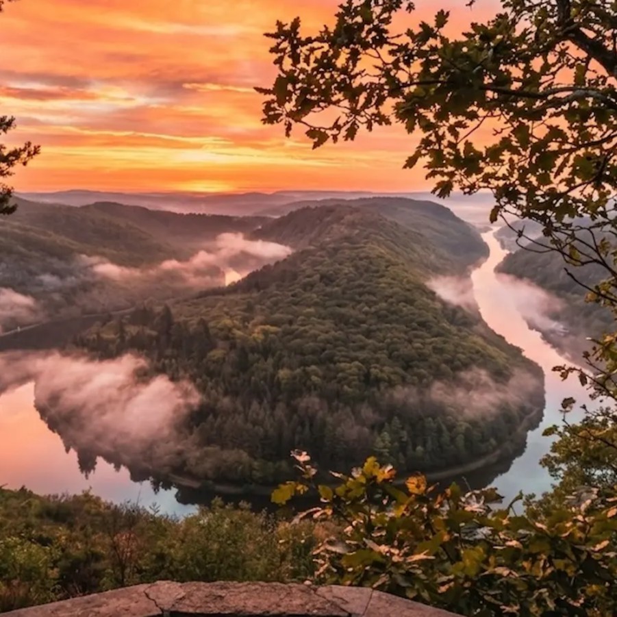 Aussicht auf die Saarschleife bei Mettlach mit Wald, Fluss und Sonnenaufgang.